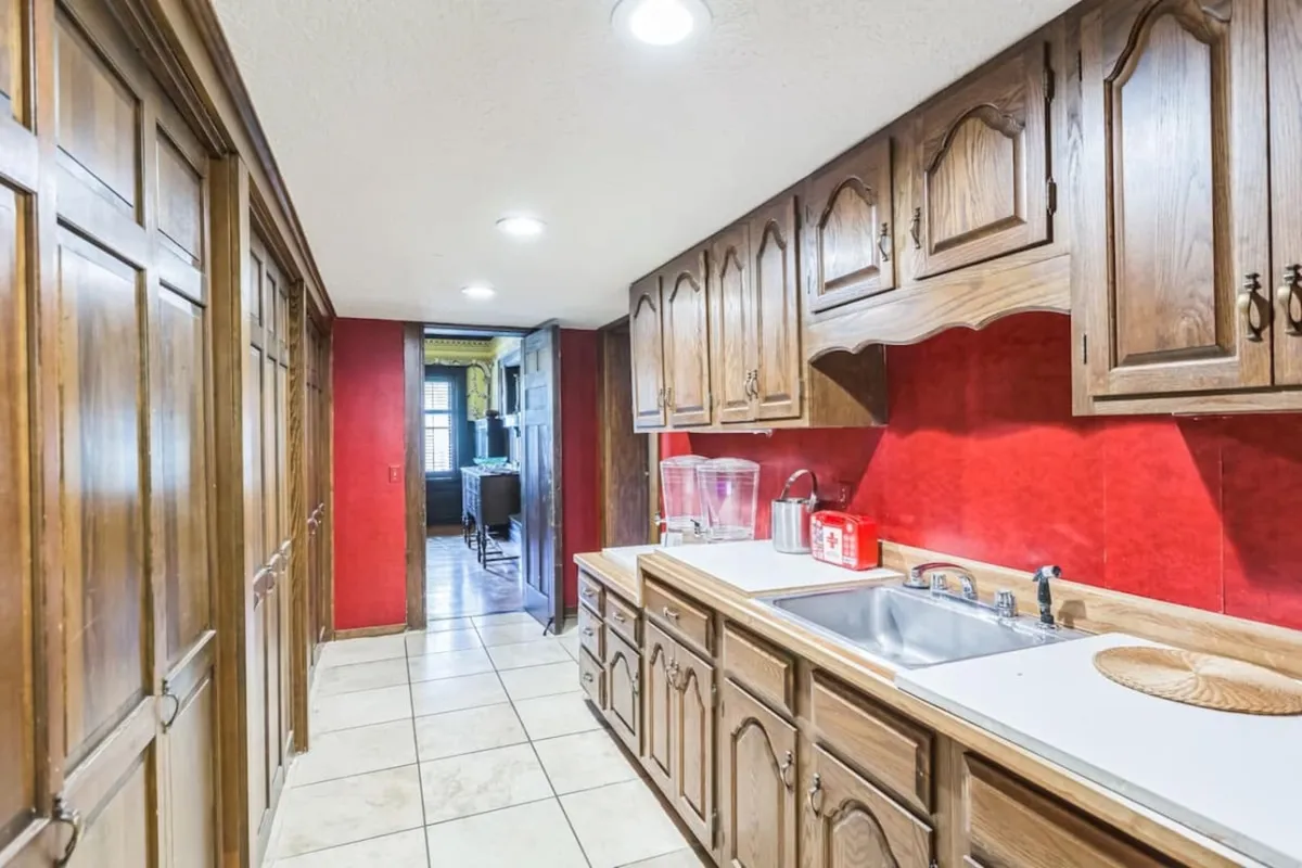 The kitchen features rich wooden cabinetry, a bold red accent wall, and a generous counter area surrounding the sink. The space feels inviting and is clearly set up for cooking, hosting family gatherings, and casual entertaining.